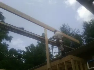 Carpenter setting a ridge beam over a new addition frame — Ice Dam Removal by Roofing Brothers in Loysville