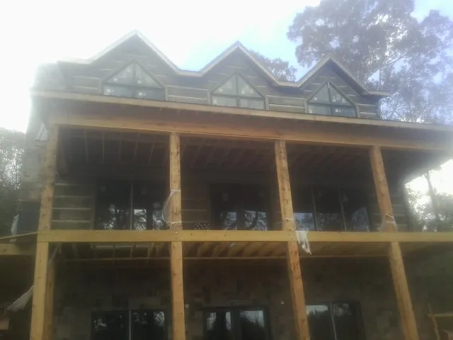 Dormers and porch framing on a large log home under construction — Roof Coating work by our crew in Loysville