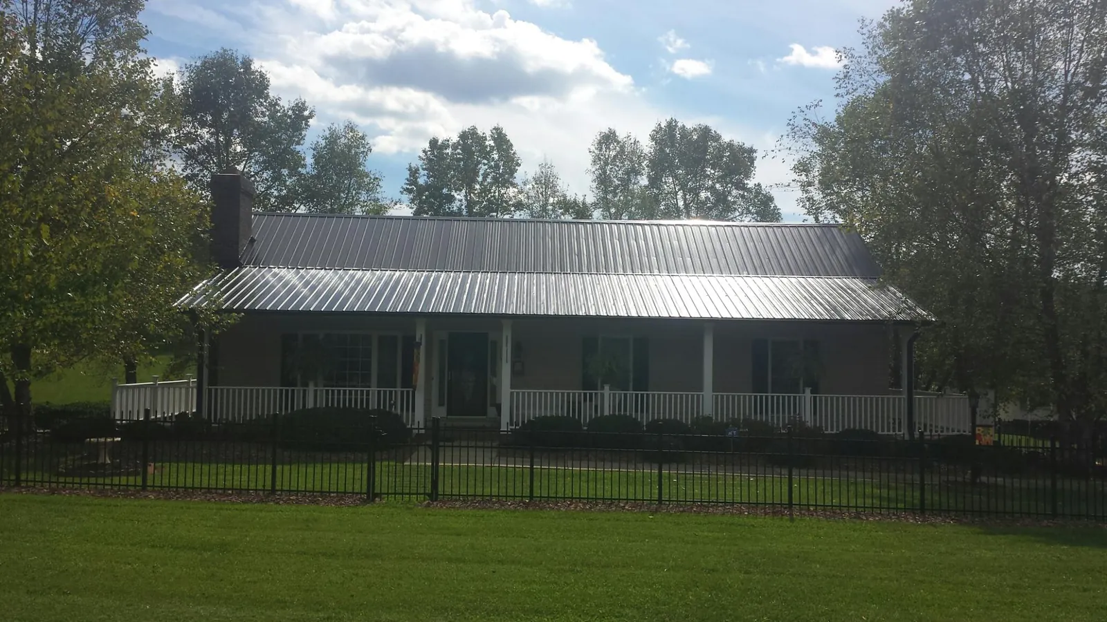 Gray metal roof on a brick ranch with a full width front porch — Gutter Guard Installation work by our crew in Loysville