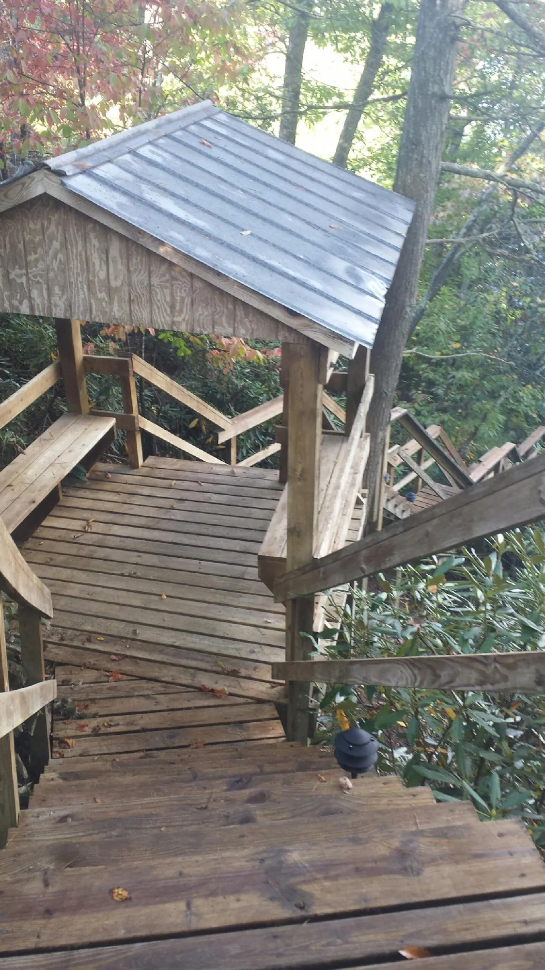 Metal roofed shelter over wooden steps on a wooded walkway — Skylight Repair & Installation work by our crew in Loysville