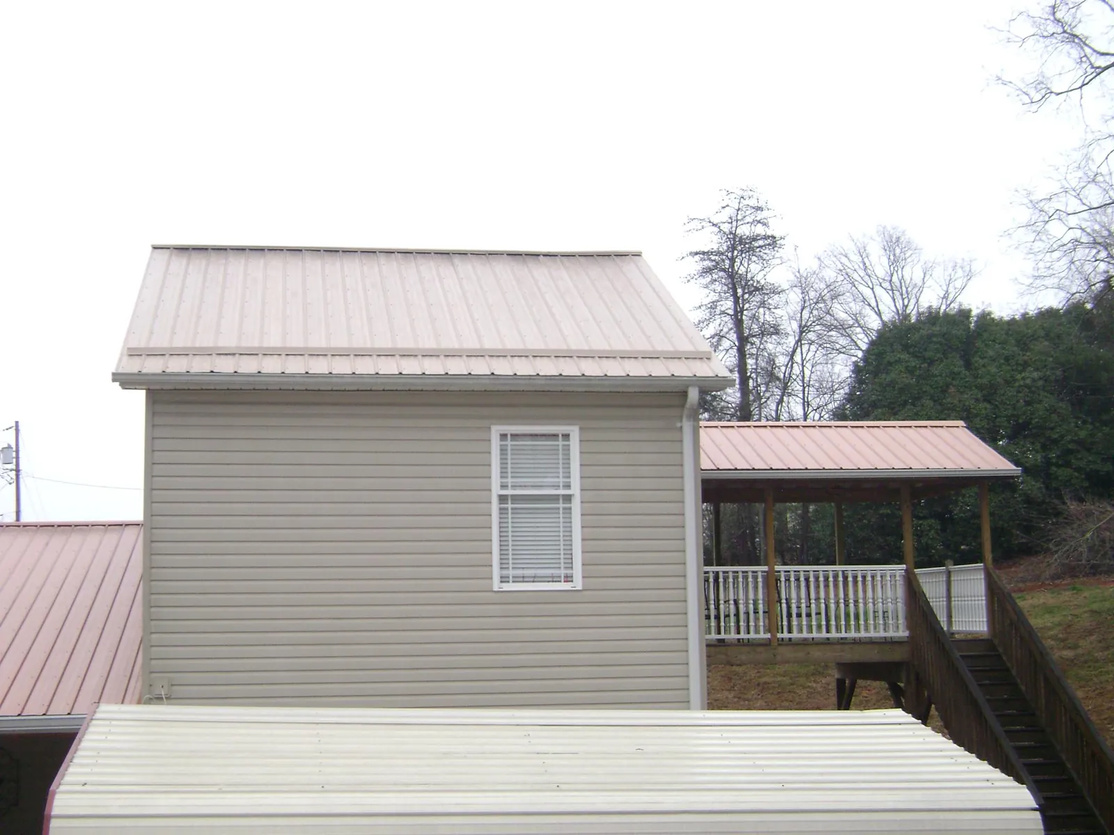 Tan metal roofs on a two story addition and attached porch, from a Roof Replacement job in Loysville