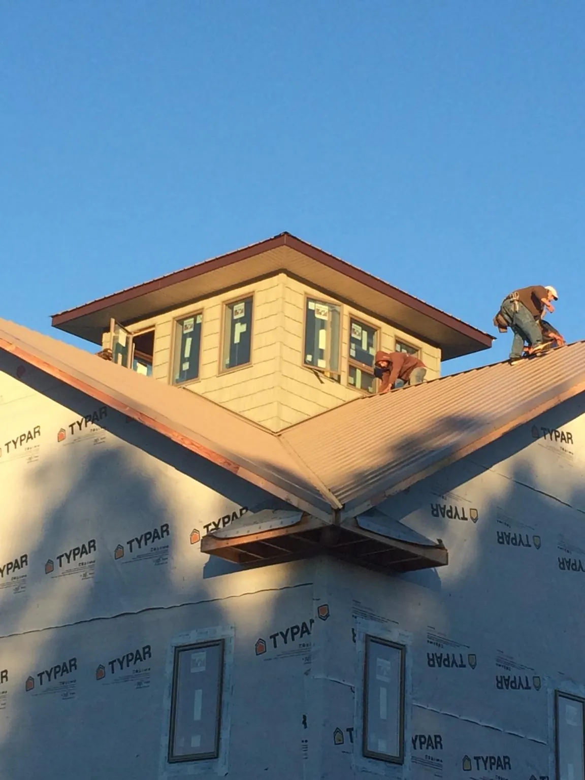 Roofers working around a rooftop cupola on a new metal roof at sunset — Roof Waterproofing in Loysville by Roofing Brothers